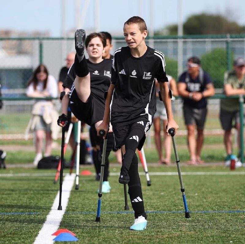 Two youngsters cross the pitch together on their crutches